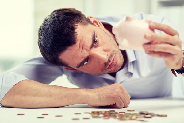 Businessman with piggy bank and coins at office Stock Picture