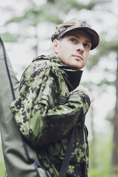 Young soldier or hunter with gun in forest — Stock Photo, Image