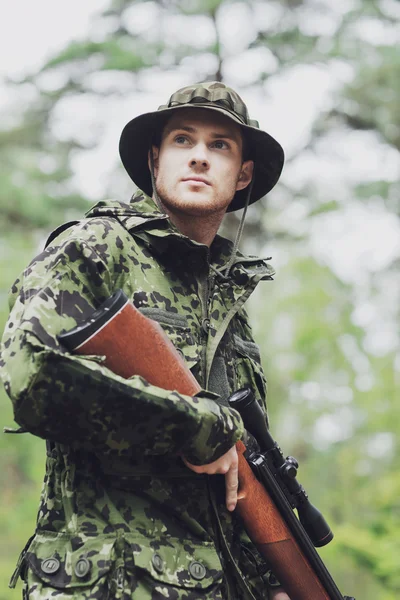 Young soldier or hunter with gun in forest — Stock Photo, Image