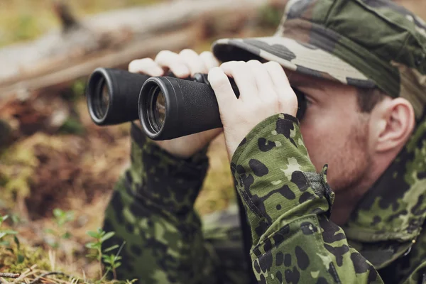 Young soldier or hunter with binocular in forest — Stock Photo, Image
