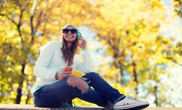 Gelukkig jonge vrouw met smartphone en hoofdtelefoons — Stockfoto