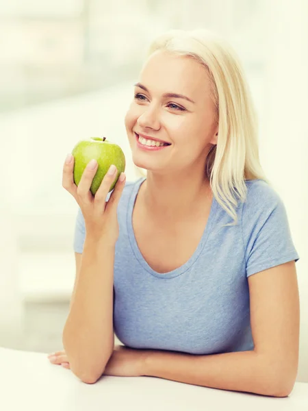 Mulher feliz comer maçã verde em casa — Fotografia de Stock