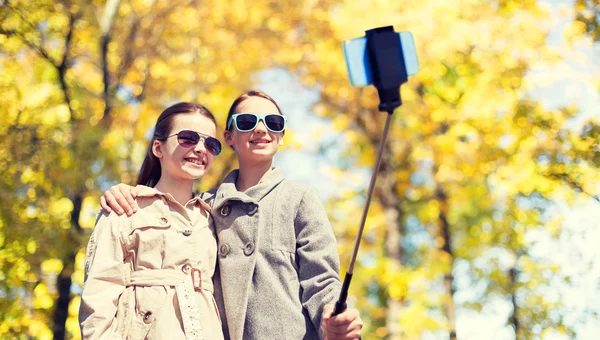 Filles heureuses avec smartphone selfie stick — Photo