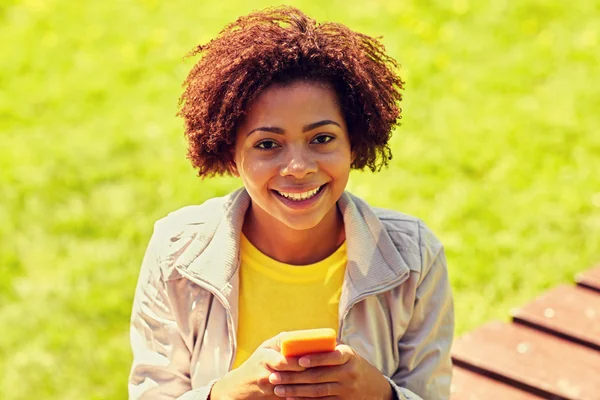 Gelukkig Afrikaanse jonge vrouw messaging op smartphone — Stockfoto