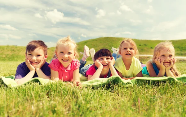 Group of kids lying on blanket or cover outdoors — Stock Photo, Image