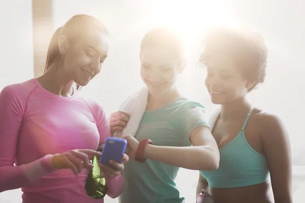 Femmes heureuses montrant le temps sur la montre du poignet dans la salle de gym — Photo