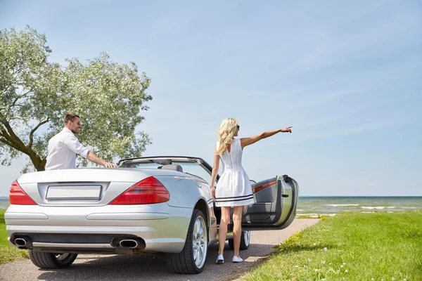 Happy man and woman near cabriolet car at sea — Stock Photo, Image