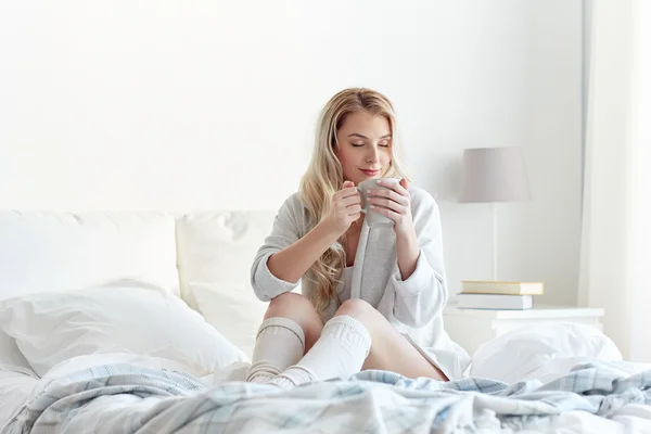 Donna felice con una tazza di caffè a letto a casa — Foto Stock