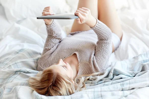 Счастливая молодая женщина с планшетным компьютером в постели дома — стоковое фото