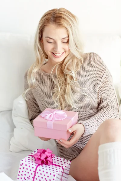 Happy young woman with gift boxes in bed at home — Stock Photo, Image