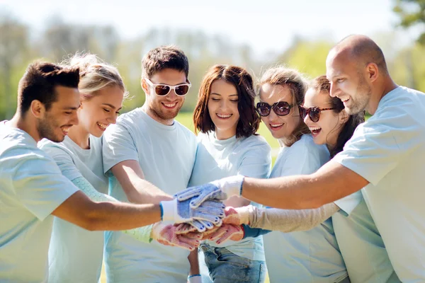 Grupo de voluntários colocando as mãos no topo no parque — Fotografia de Stock