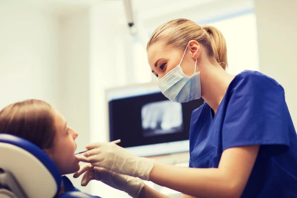 Dentista femenino chequeando dientes de niña paciente —  Fotos de Stock