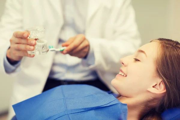 Dentista feliz mostrando layout da mandíbula para menina paciente — Fotografia de Stock