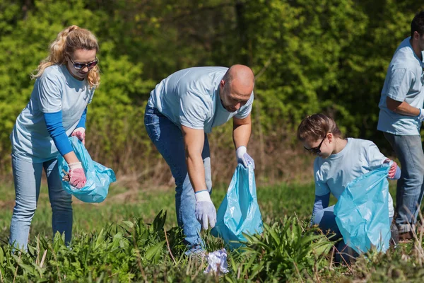 Voluntários com sacos de lixo área do parque de limpeza — Fotografia de Stock