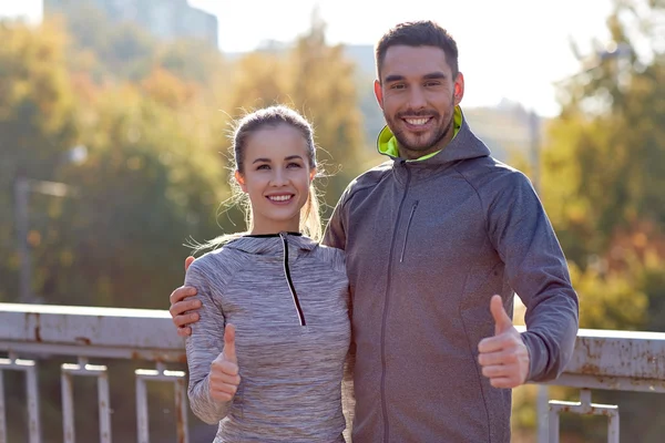 Leende par visar tummen upp utomhus — Stockfoto