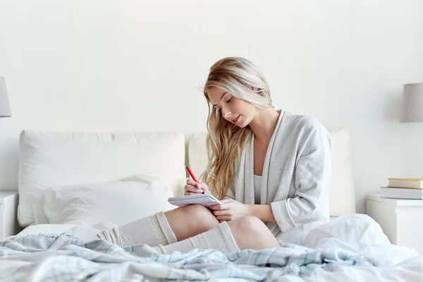 Heureuse jeune femme avec ordinateur portable dans le lit à la maison — Photo