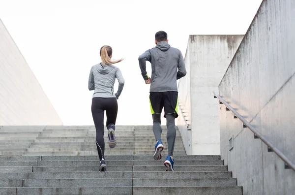 Couple running upstairs on city stairs — Stock Photo, Image