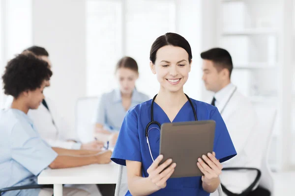 Happy doctor with tablet pc over team at clinic — Stock Photo, Image