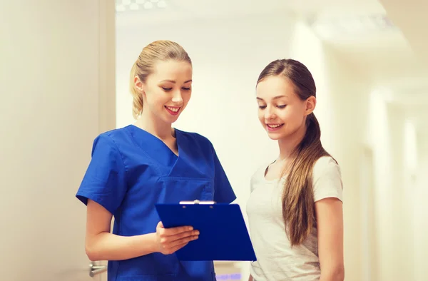 Doctor or nurse with clipboard and girl patient — Stock Photo, Image