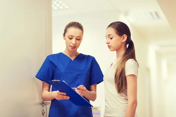 Doctor or nurse with clipboard and girl patient — Stock Photo, Image