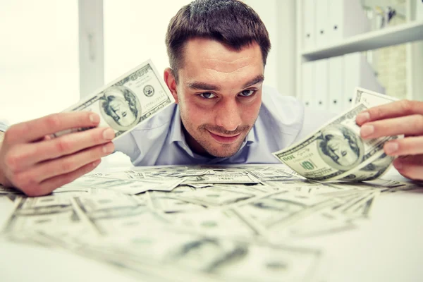 Hombre de negocios feliz con un montón de dinero en la oficina —  Fotos de Stock