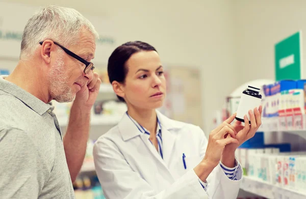 Farmacéutico mostrando droga al hombre mayor en la farmacia — Foto de Stock