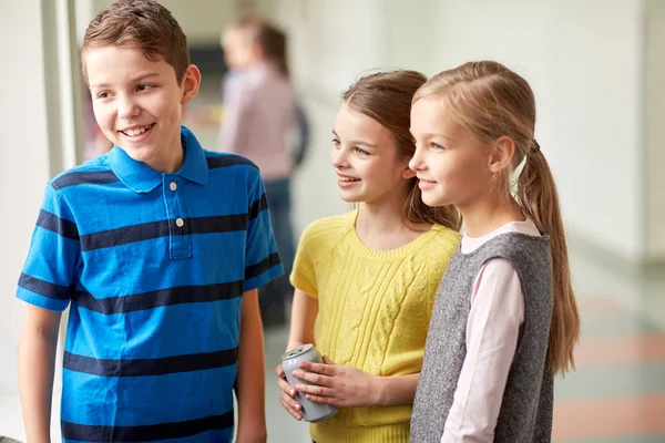 Skupina s úsměvem školní děti mluví v chodbě — Stock fotografie