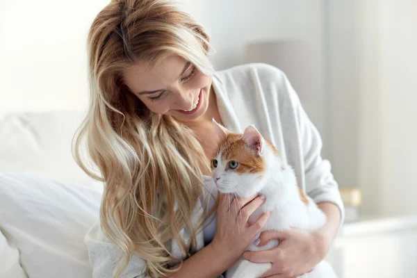Щаслива молода жінка з кішкою в ліжку вдома — стокове фото