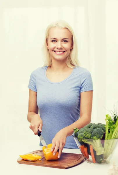 Sorrindo jovem mulher cortando legumes em casa — Fotografia de Stock