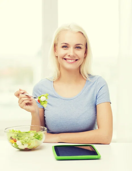 Donna sorridente mangiare insalata con tablet pc a casa — Foto Stock