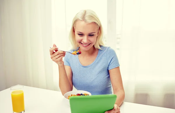 Woman with tablet pc eating breakfast at home — Stock Photo, Image