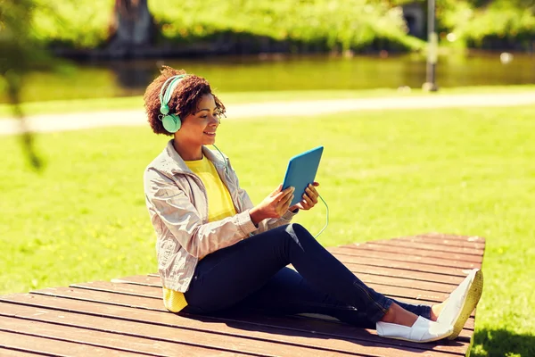 Happy african woman with tablet pc and headphones — Stock Photo, Image