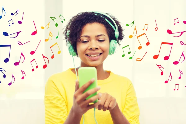 Mujer africana feliz con teléfono inteligente y auriculares —  Fotos de Stock