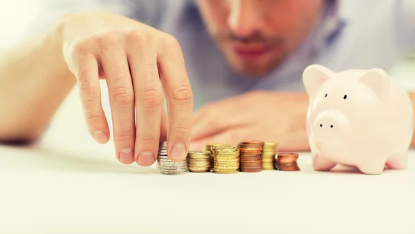 Close up de homem de negócios com banco porquinho e moedas — Fotografia de Stock