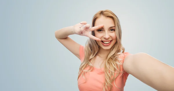 Lachende vrouw nemen selfie en tonen vredesteken — Stockfoto