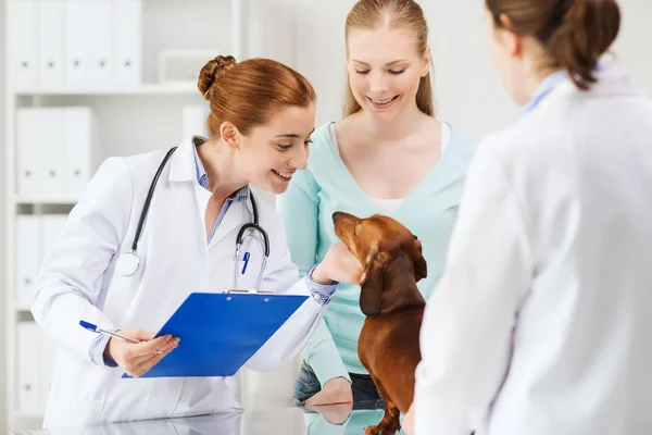 Счастливая женщина с собакой и врачом в ветеринарной клинике — стоковое фото