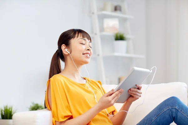 Felice donna asiatica con tablet pc e auricolari — Foto Stock