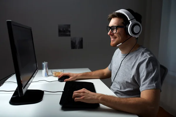 Hombre en auriculares jugando videojuego de ordenador en casa —  Fotos de Stock