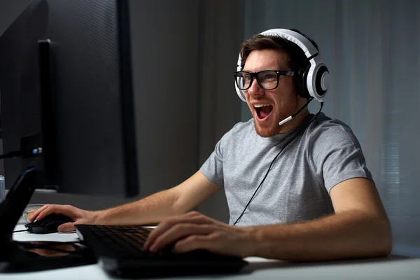 Homem em fone de ouvido jogando jogo de computador em casa — Fotografia de Stock