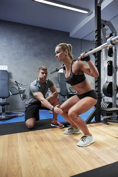 Uomo e donna con muscoli flettenti bar in palestra — Foto Stock