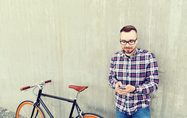 Homem hipster em fones de ouvido com smartphone e bicicleta — Fotografia de Stock