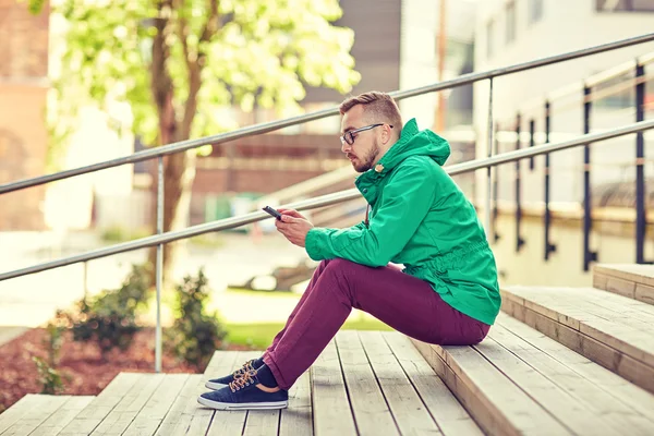 Hipster młody człowiek z smartphone w mieście — Zdjęcie stockowe