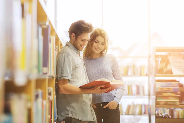 Lycklig student par med böcker i biblioteket — Stockfoto