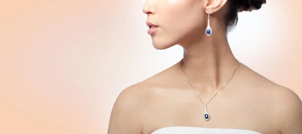 Close up of woman with earring and pendant — Stock Photo, Image