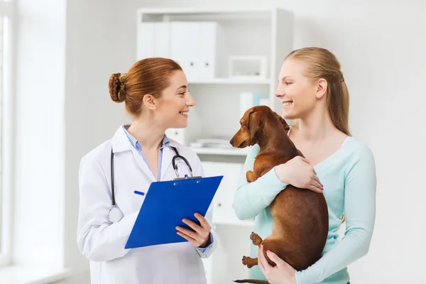 Mulher feliz com cão e médico na clínica veterinária — Fotografia de Stock