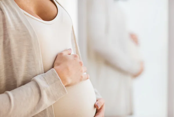 Gros plan du ventre de la femme enceinte au miroir — Photo