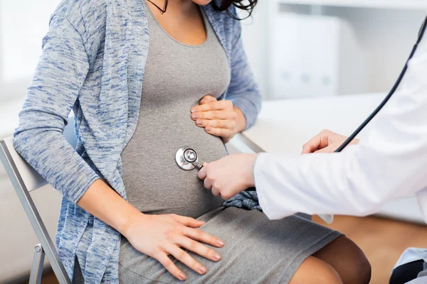 Médico con estetoscopio y vientre de mujer embarazada —  Fotos de Stock