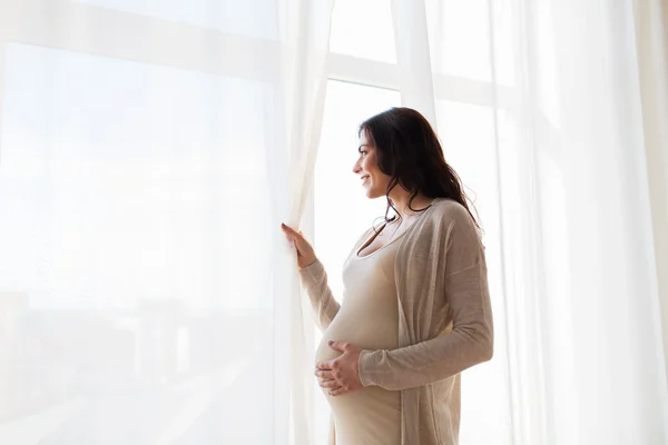 Primer plano de la mujer embarazada feliz mirando a la ventana — Foto de Stock