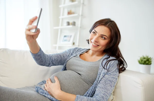 Kobieta w ciąży, biorąc smartphone selfie w domu — Zdjęcie stockowe