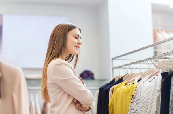 Gelukkig jonge vrouw kleding in winkelcentrum kiezen — Stockfoto